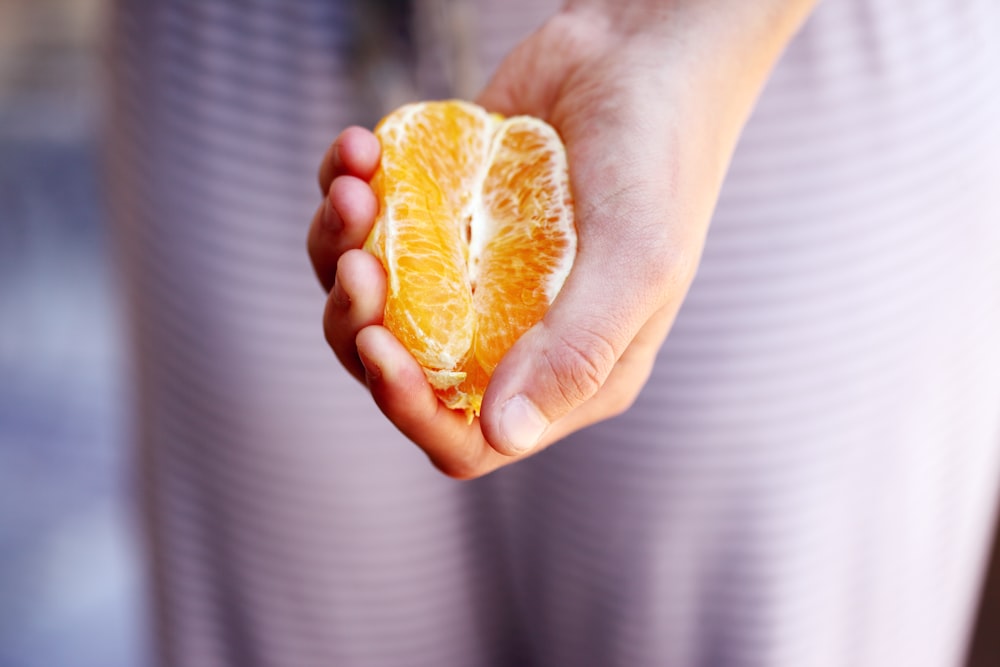 Photographie sélective de la personne pressant un fruit orange