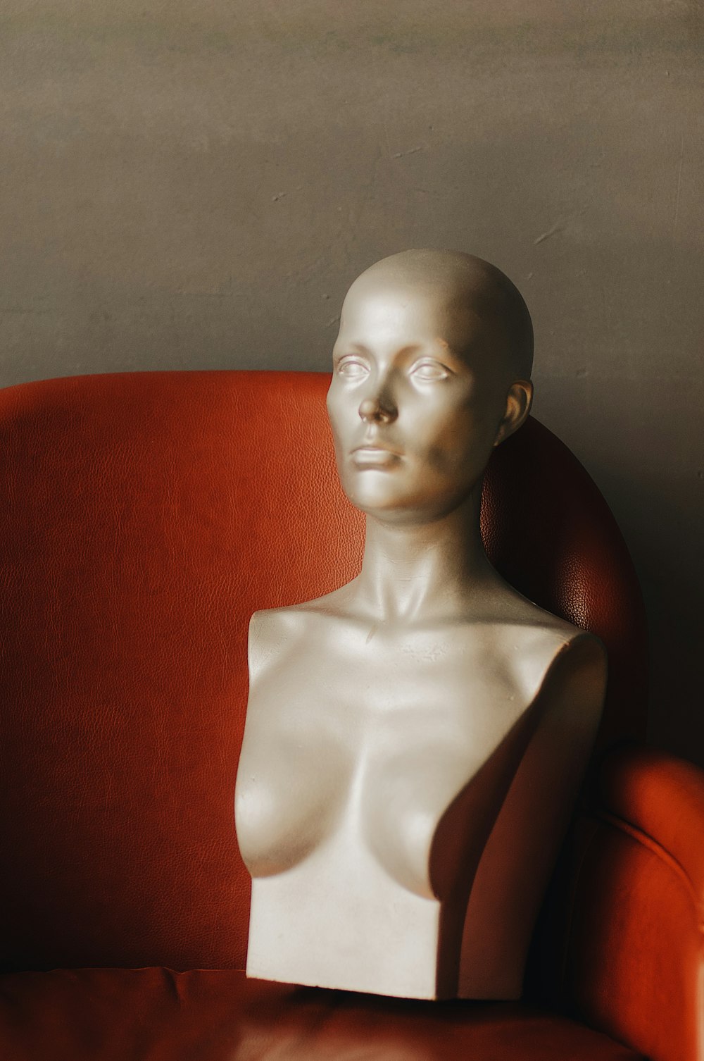 half-body mannequin on red leather chair