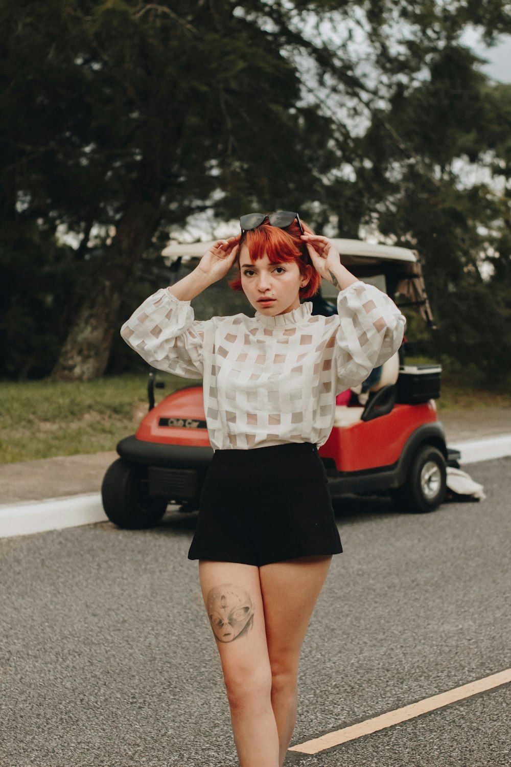 woman standing on street near red golf cart during daytime