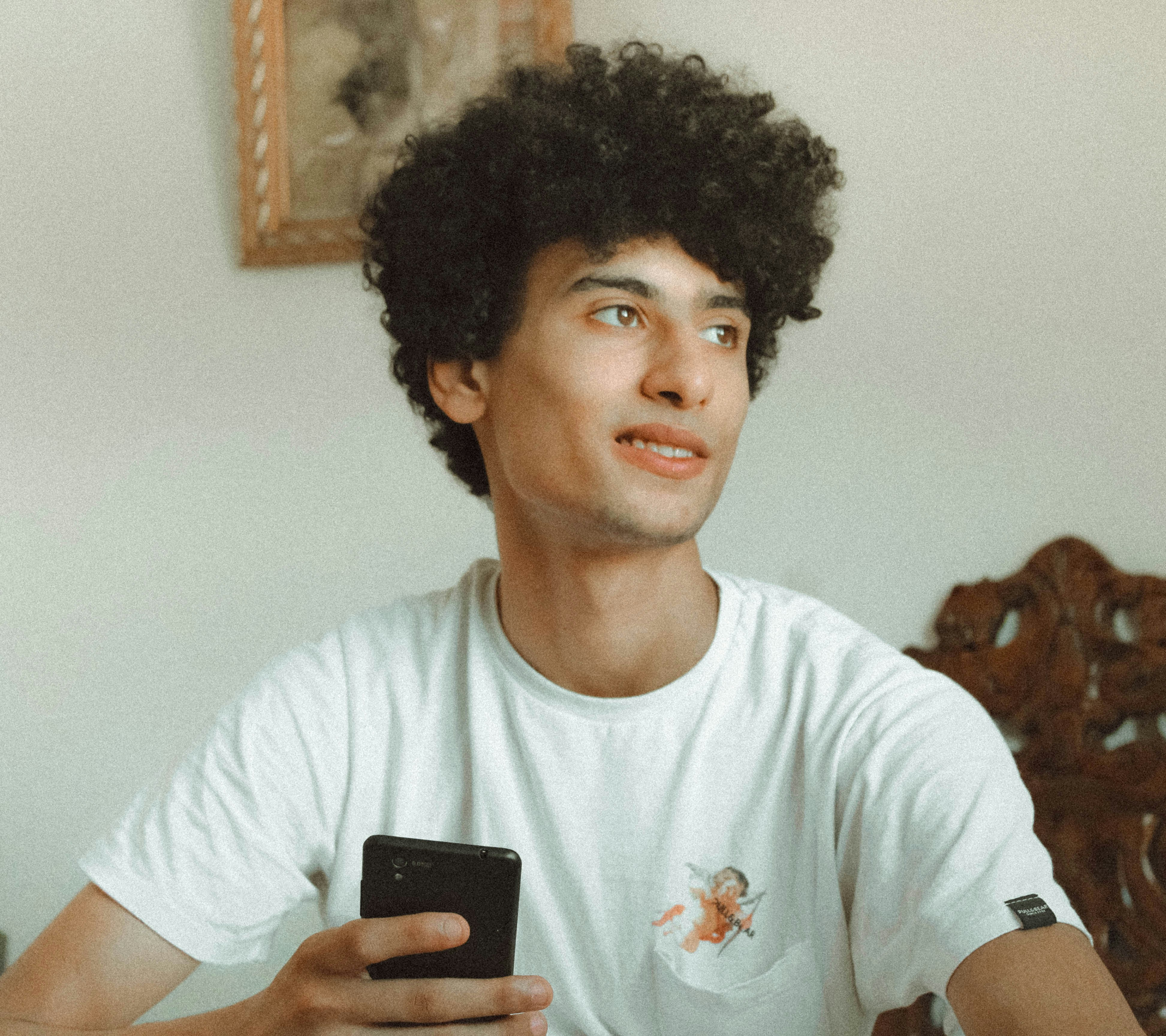 Image of a person smiling and looking relaxed while playing a game on their phone - block blast unblocked