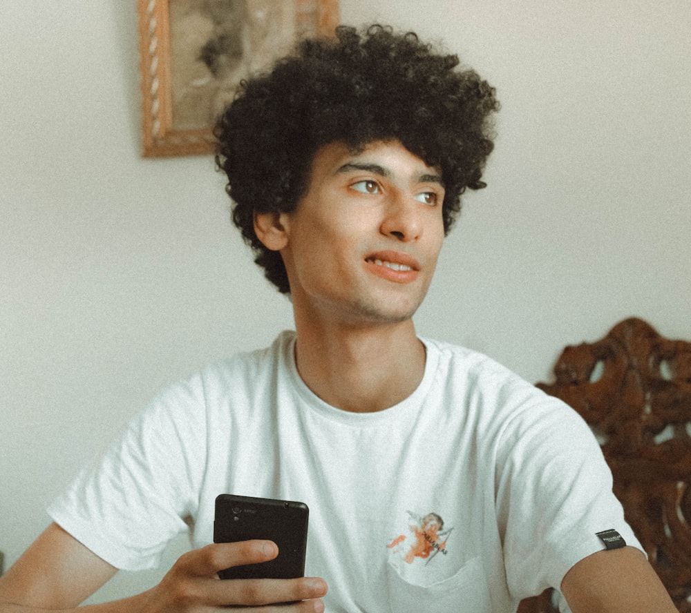 smiling man wearing white shirt holding smartphone