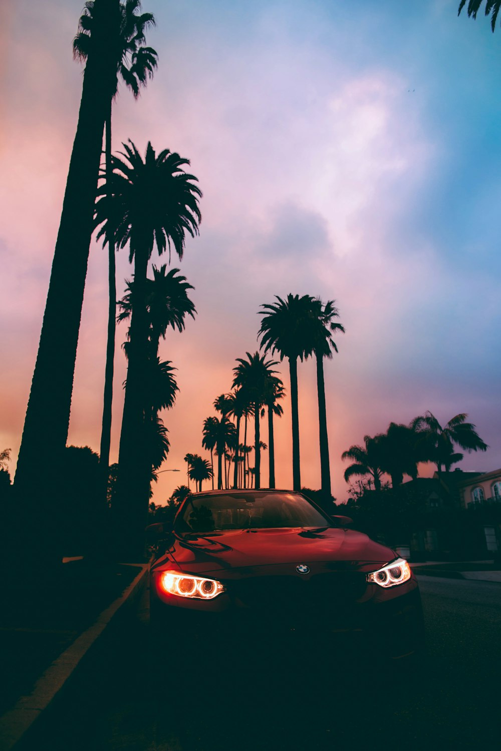 red sports car on park beside road with tree lines during daytime