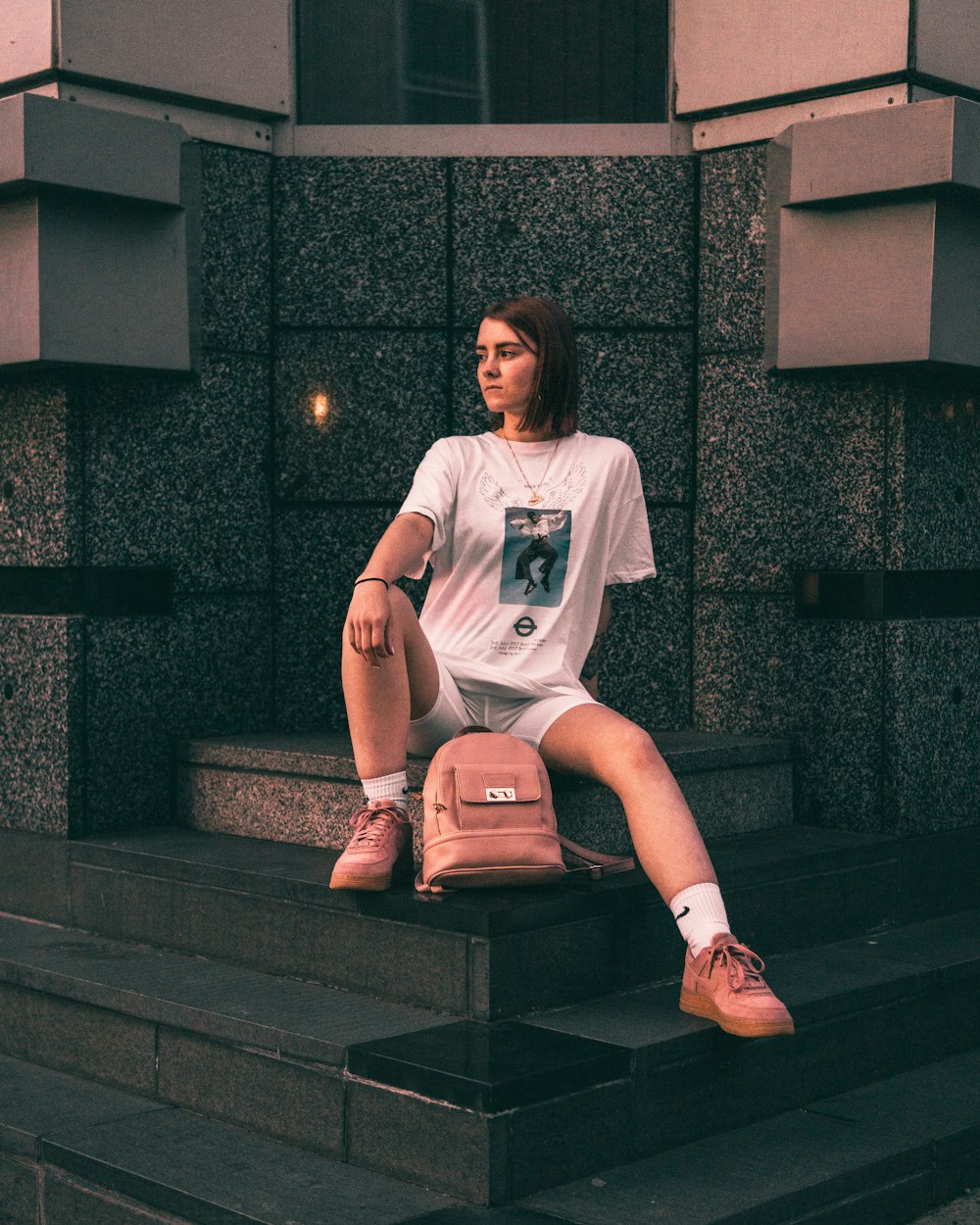 Femme en T-shirt blanc assise sur une surface en béton