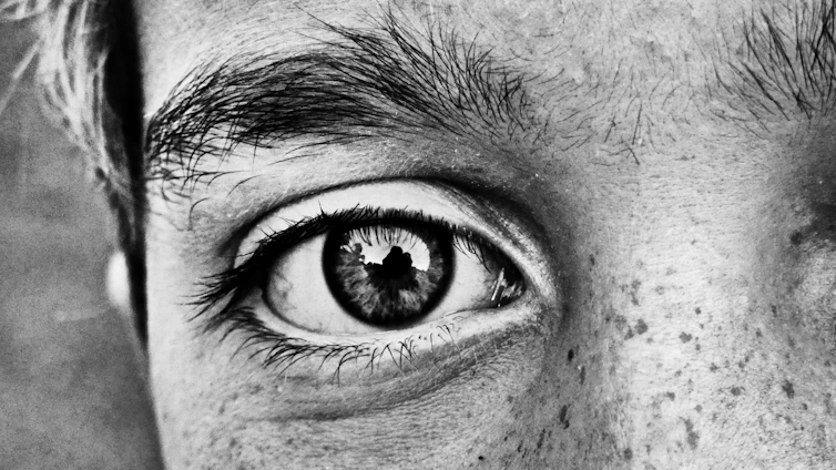 Close-up of a human eye reflecting cosmic patterns, hinting at universal symbolism.