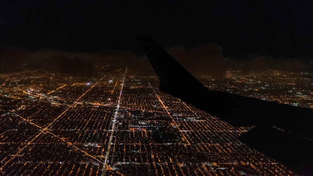 an airplane wing flying over a city at night