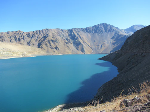 The serene blue waters of Attabad Lake framed by rugged mountains under a clear sky.