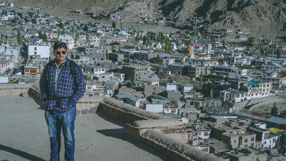 man standing on a rooftop overlooking a village