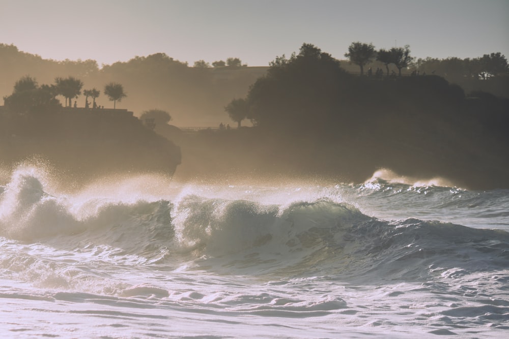 large sea wave with silhouette trees and mountain