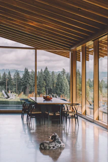 The dining area set for a meal with natural wood tables and views of the forest.
