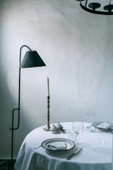 A minimalist dining table set with elegant tableware and a centerpiece of fresh flowers.