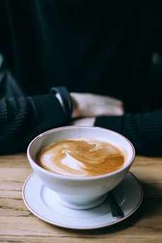 Close-up of a steaming cup of freshly brewed coffee on a rustic wooden table with soft morning light.
