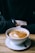 A close-up of a steaming cup of specialty coffee on a rustic wooden table.