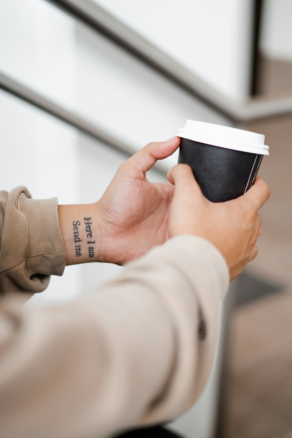 personne tenant une tasse à café noire et blanche