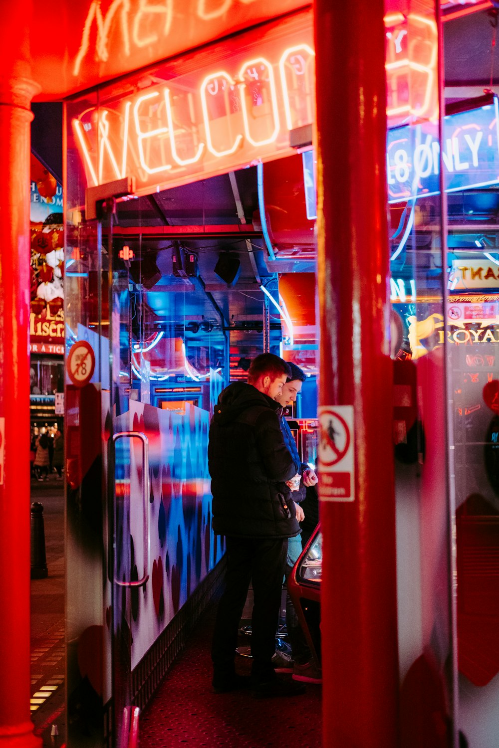 man and woman standing under welcome signage at night