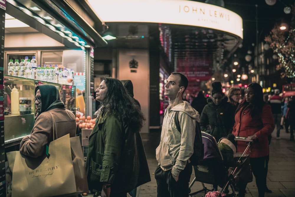 people fall in line beside store during night time