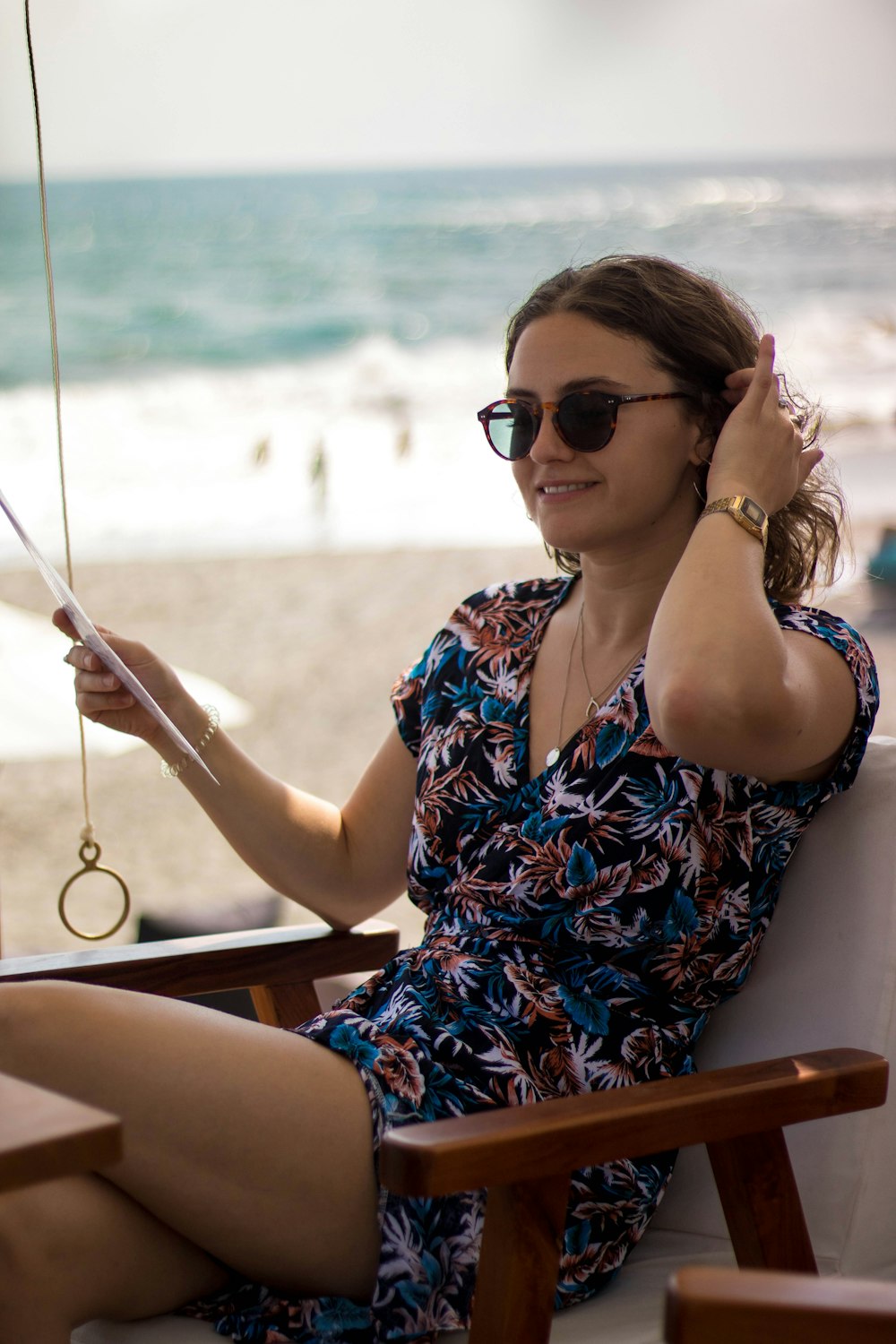 smiling woman wearing v-neck midi dress with sunglasses sitting on armchair