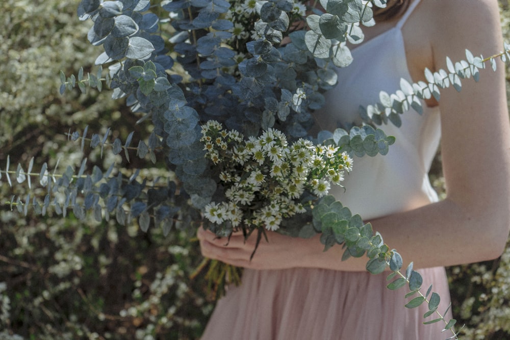 mujer sosteniendo ramo de flores de pétalos blancos