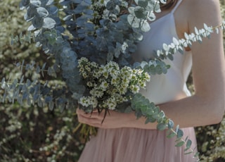 woman holding white petaled flower bouquet