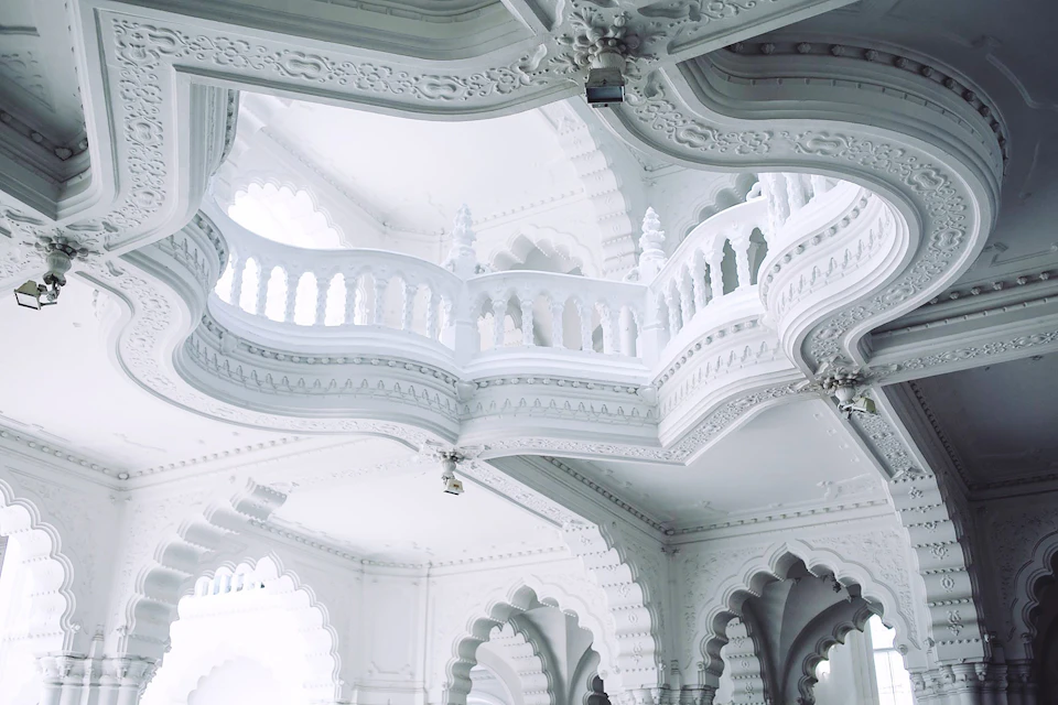 Grand white architectural structure with intricate designs and patterns dominates the room's space