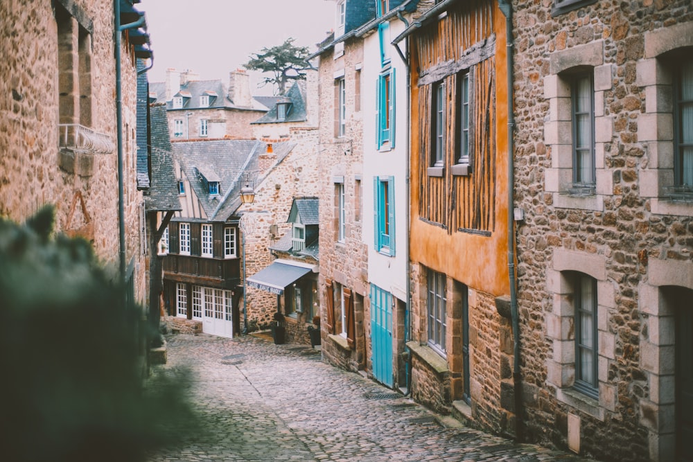 a narrow alley with stone buildings and blue shutters