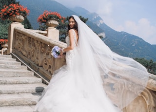 bride holding bouquet standing on white stairs