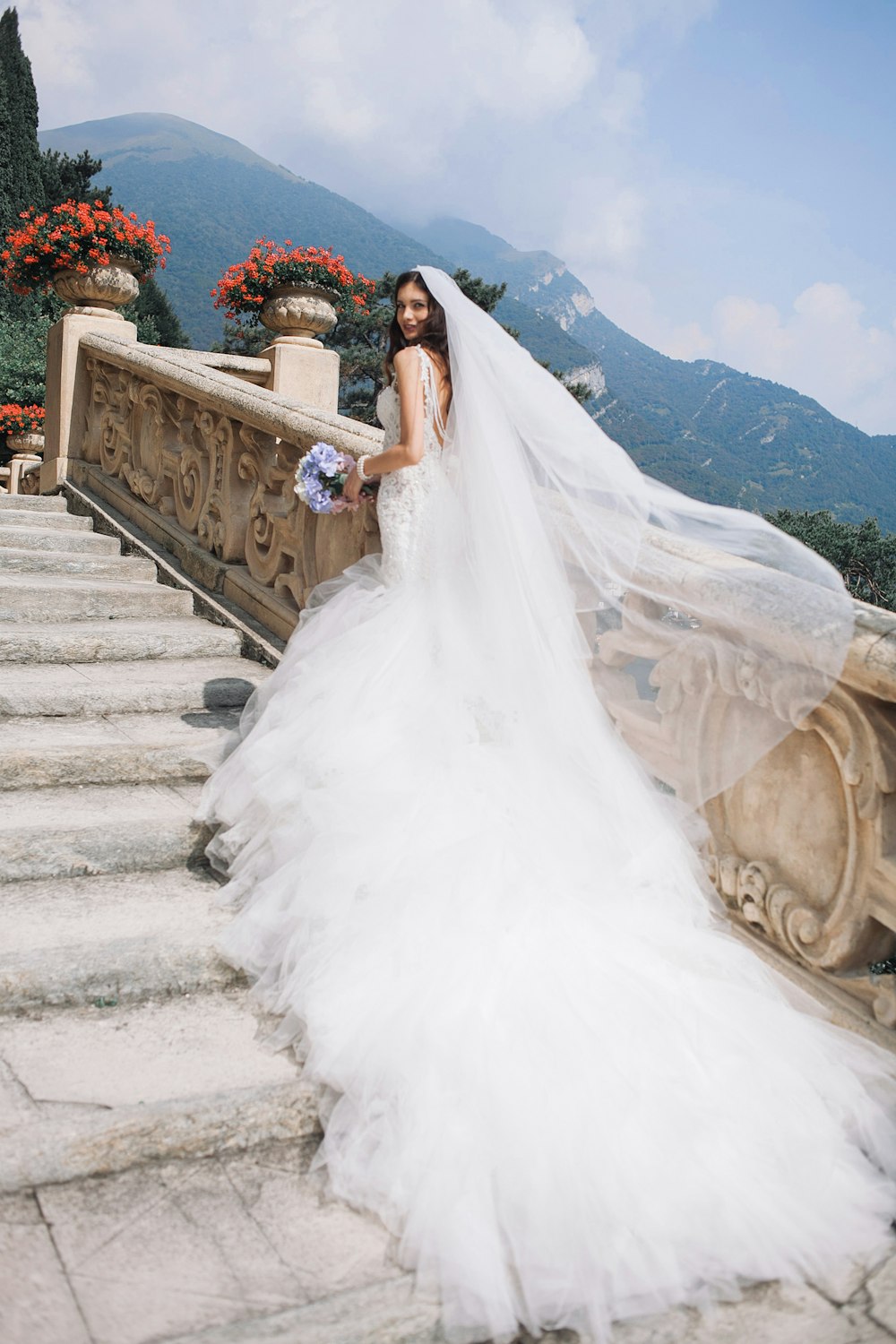 novia sosteniendo ramo de pie en escaleras blancas