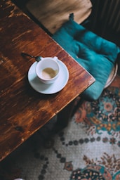 empty white ceramic mug and saucer on brown table