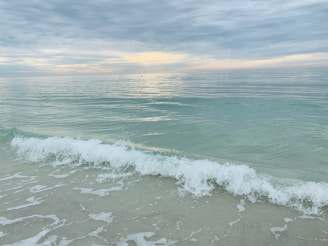 A quiet beach with turquoise waves gently lapping the shore at dawn.