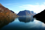 A tranquil lake reflecting autumn foliage and mountains.