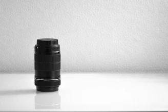 A sleek black and white close-up of a camera lens reflecting a subtle grid pattern.