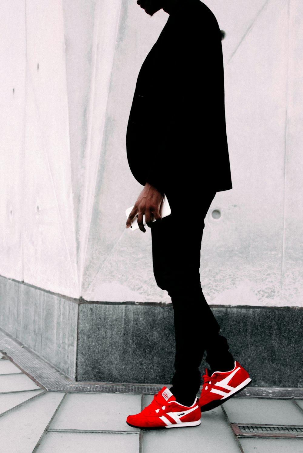 man wearing black suit jacket and red sneakers