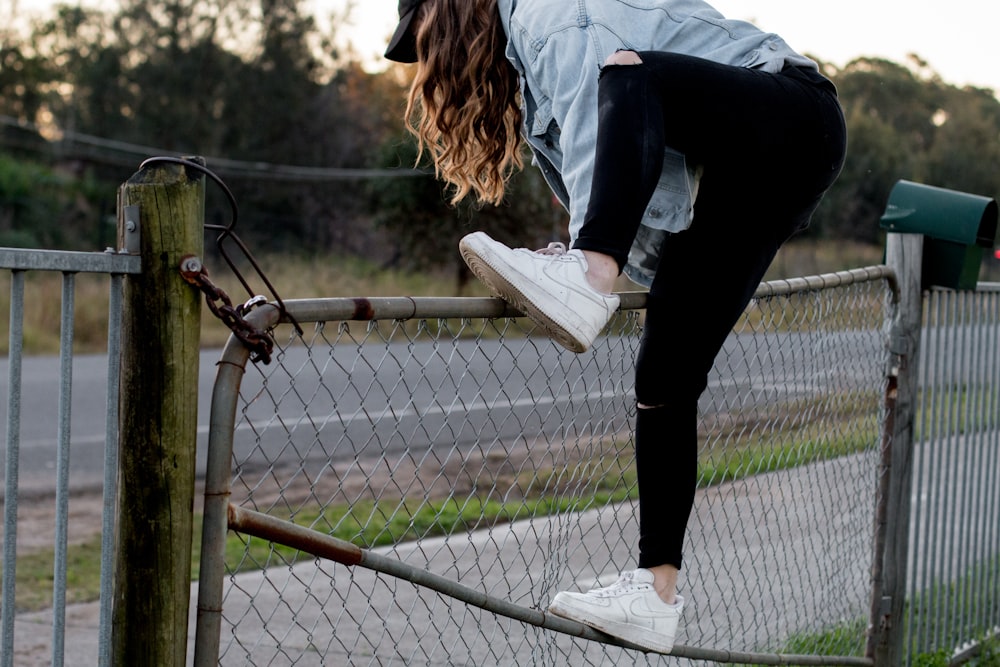 woman climbing over fence