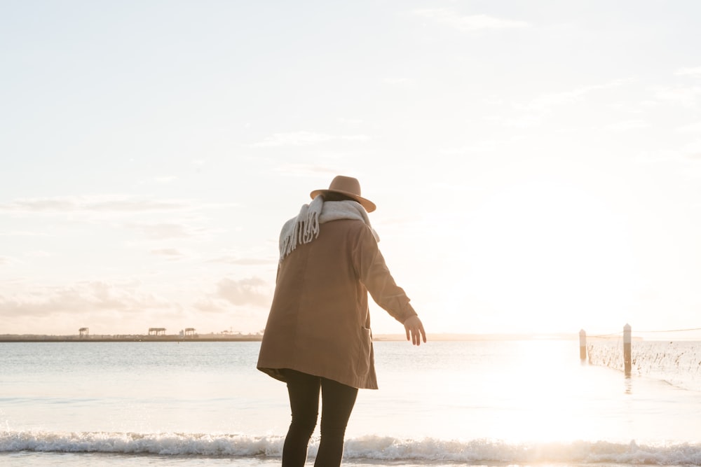 woman standing on shore during golden hour