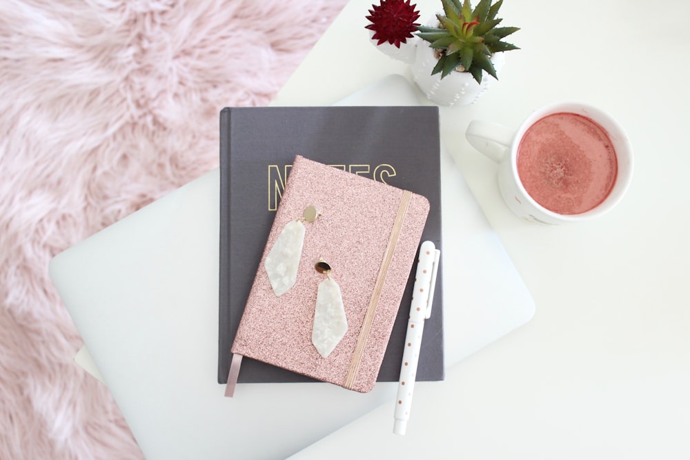 brown book on black book beside white ceramic mug