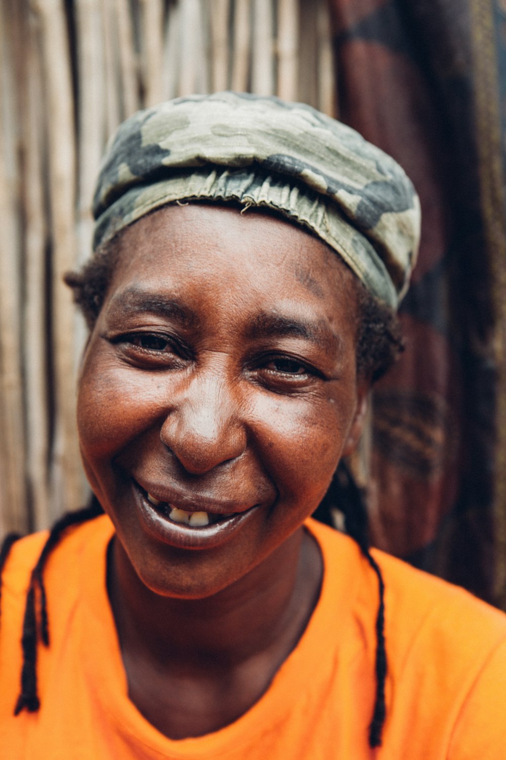 Mulher na camisa amarela da gola da tripulação sorrindo perto da parede marrom