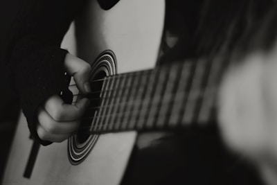 Close-up of musician's hands strumming a classic acoustic guitar with sepia tones