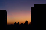 Smooth transitions of sunset orange waves over a grey cityscape silhouette.