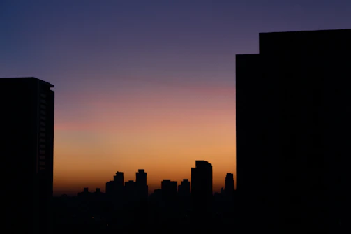 Smooth transitions of sunset orange waves over a grey cityscape silhouette.
