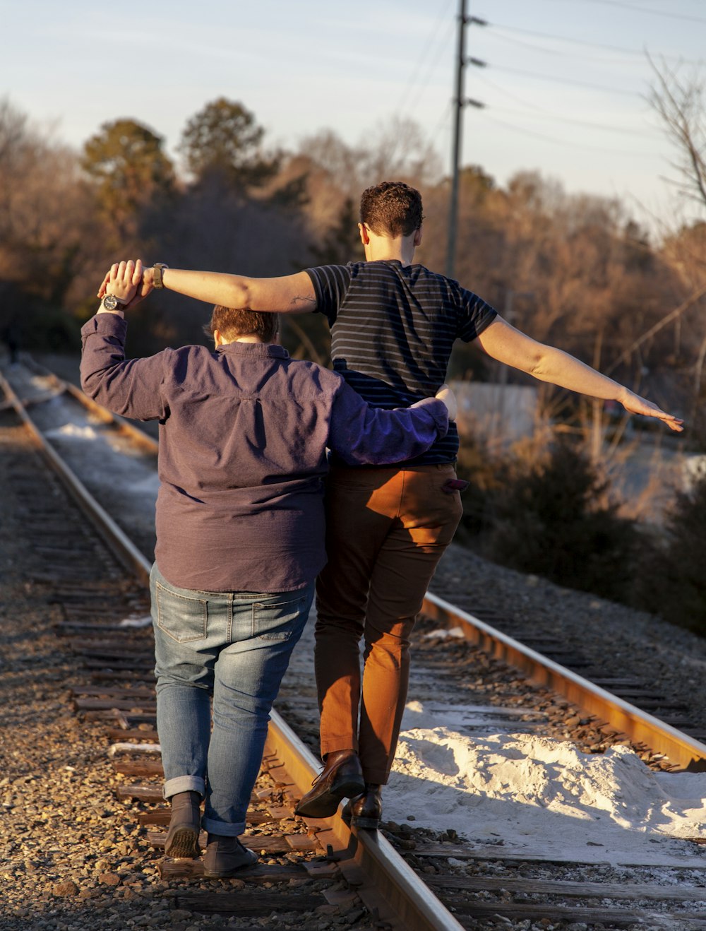 two person walking on railroad on focus photography