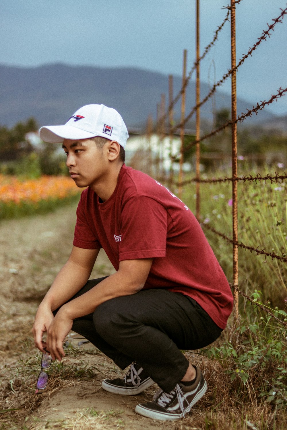 man wearing red shirt sitting beside grass