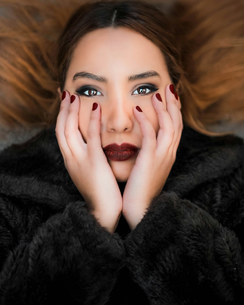 woman lying while holding her face with both hands