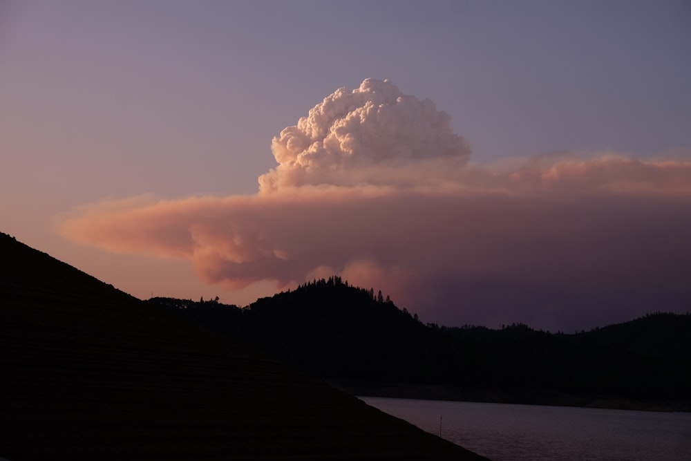 silhouette of mountain near body of water during cloudy day