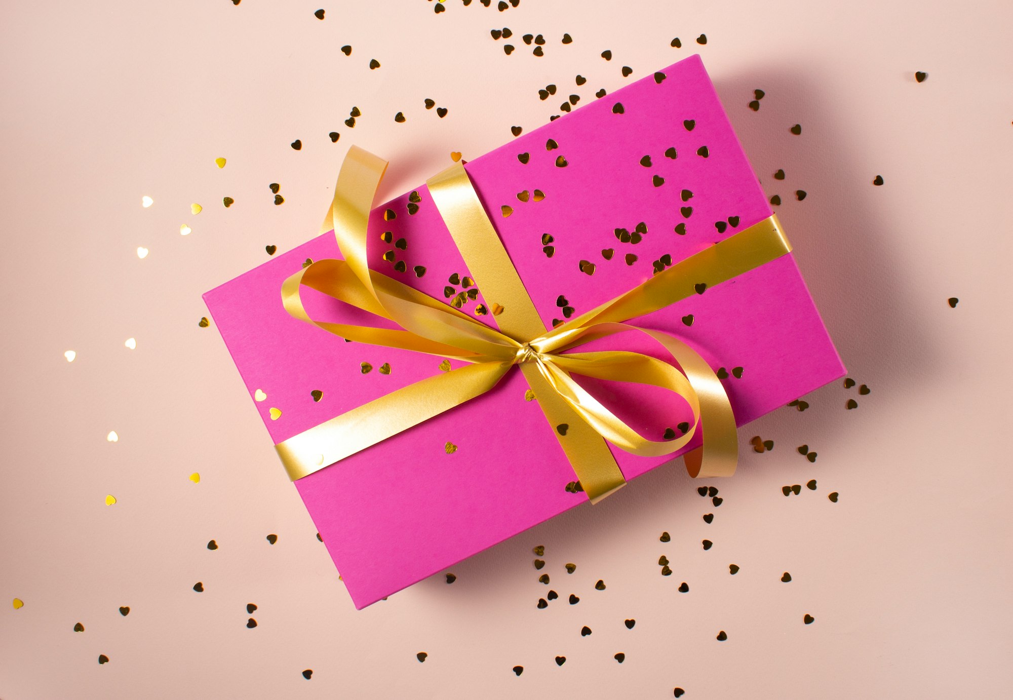 A pink gift box with a gold ribbon.