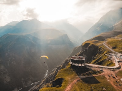 person paragliding on mountain cliff during daytime georgia teams background