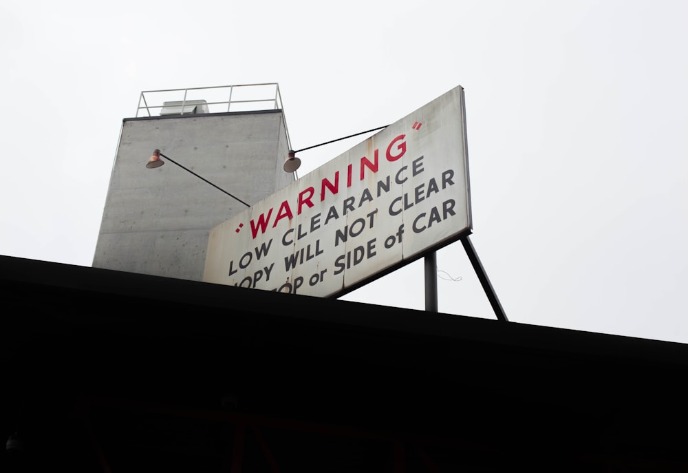 tilt shoot of white and black Warning signage during daylight