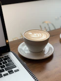 Close-up of a perfectly crafted latte next to a laptop, highlighting the workspace-friendly vibe.