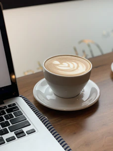 Close-up of a perfectly crafted latte next to a laptop, highlighting the workspace-friendly vibe.