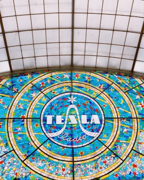 Portrait of Nikola Tesla illuminated by a faint purple glow, framed by dark shadows.