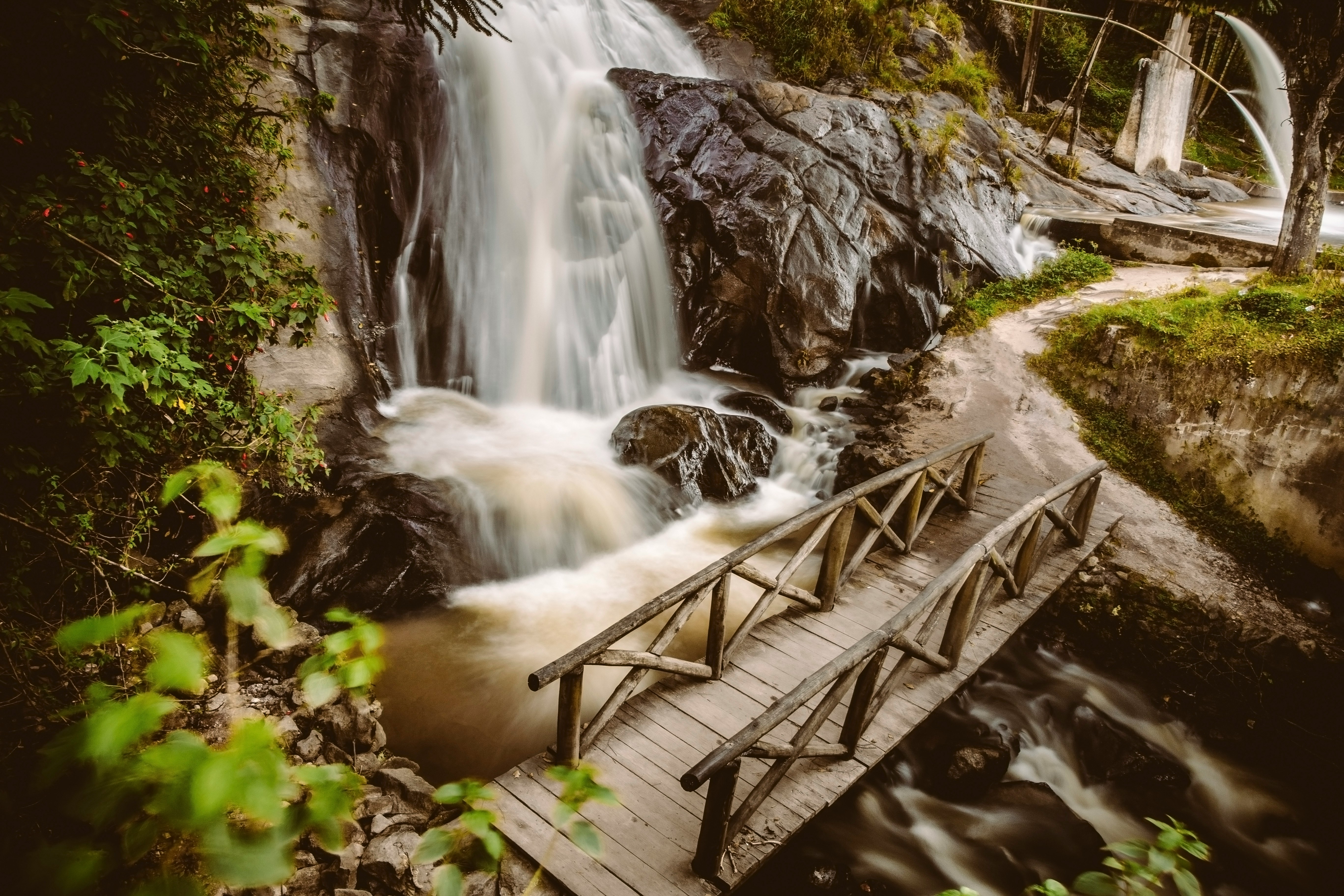 brown wooden bridge near waterfall