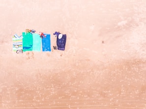 A collection of colorful beach towels laid out on the sand.